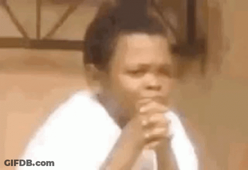 A Young Boy Is Sitting With His Hands Folded In Prayer . GIF