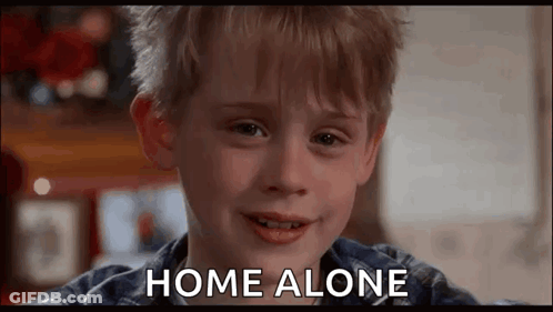 A Young Boy Is Smiling And Saying `` Home Alone '' While Looking At The Camera . GIF