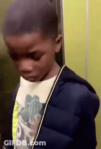 A Young Boy Is Standing In An Elevator Wearing A Blue Jacket And A Cactus Shirt . GIF