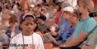 A Young Boy Is Standing In Front Of A Crowd Of People . GIF