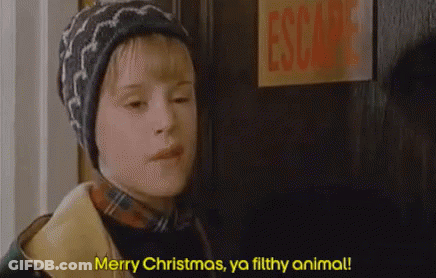A Young Boy Is Standing In Front Of A Door And Saying `` Merry Christmas , Ya Filthy Animal ! '' . GIF