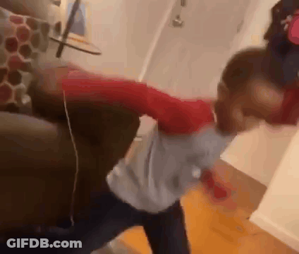 A Young Boy Is Standing Next To A Couch In A Living Room And Dancing . GIF