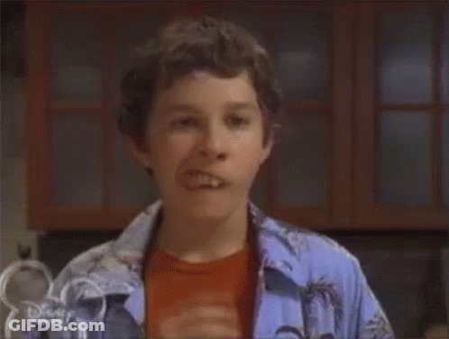 A Young Boy Is Sticking His Tongue Out While Wearing A Blue Shirt . GIF