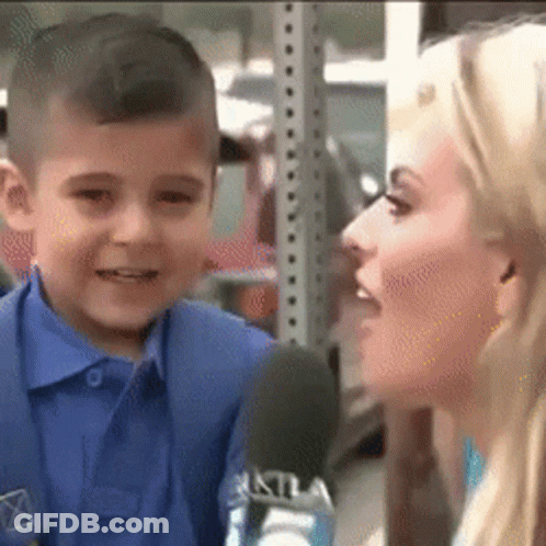 A Young Boy Is Talking Into A Microphone While A Woman Looks On . GIF
