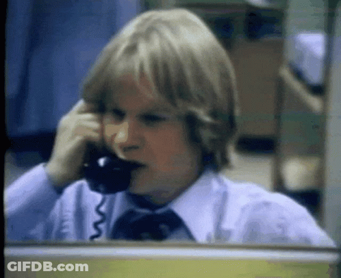 A Young Boy Is Talking On A Telephone In An Office GIF