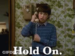 A Young Boy Is Talking On A Telephone With The Words Hold On Written On The Bottom GIF