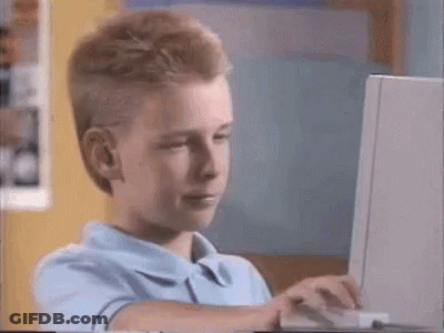 A Young Boy Is Using A Laptop Computer And Making A Funny Face . GIF