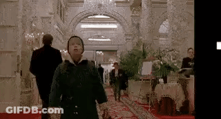 A Young Boy Is Walking Down A Hallway In A Hotel . GIF