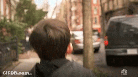 A Young Boy Is Walking Down A Street With A Van Behind Him . GIF