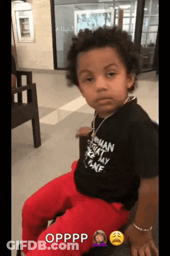 A Young Boy Is Wearing A Black Shirt That Says Opppp On It GIF