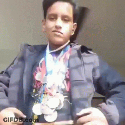 A Young Boy Is Wearing A Jacket And A Medal Around His Neck . GIF