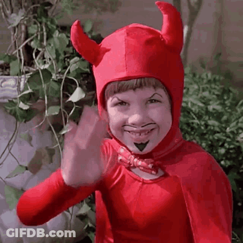 A Young Boy Is Wearing A Red Devil Costume And Waving . GIF