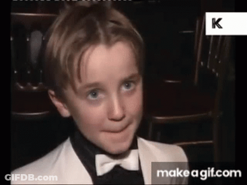 A Young Boy Is Wearing A Tuxedo And Bow Tie And Making A Funny Face . GIF