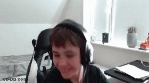 A Young Boy Is Wearing Headphones And Smiling While Sitting In A Chair . GIF