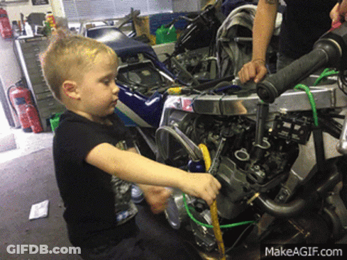A Young Boy Is Working On A Motorcycle With A Makeagif.com Watermark GIF