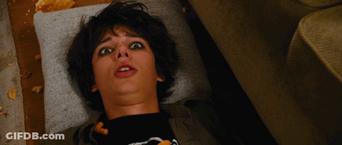 A Young Boy Laying On A Couch With His Mouth Open And A Black Shirt With A Skeleton On It GIF