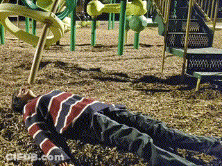 A Young Boy Laying On The Ground In A Playground GIF