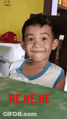 A Young Boy Making A Funny Face With The Words He.he.he. In Red Behind Him GIF