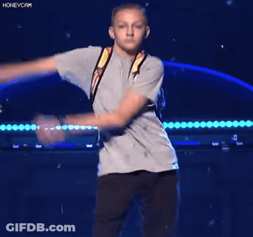 A Young Boy Wearing A Backpack Is Dancing On A Stage . GIF
