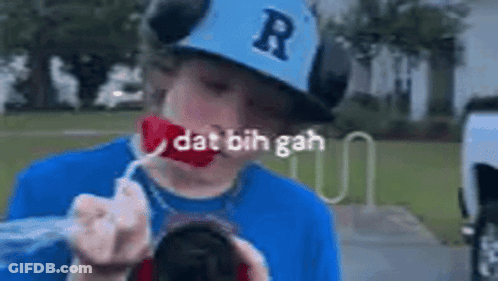 A Young Boy Wearing A Baseball Cap And A Blue Shirt Is Blowing Bubbles Out Of A Can . GIF