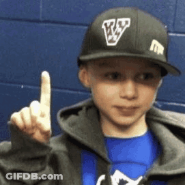 A Young Boy Wearing A Baseball Cap With The Letter V On It Is Giving The Middle Finger . GIF