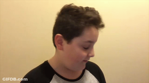 A Young Boy Wearing A Black And Gray Shirt Is Making A Funny Face GIF