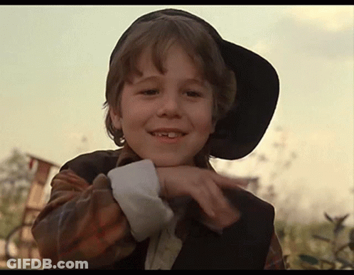 A Young Boy Wearing A Black Hat And A Plaid Shirt Is Smiling GIF