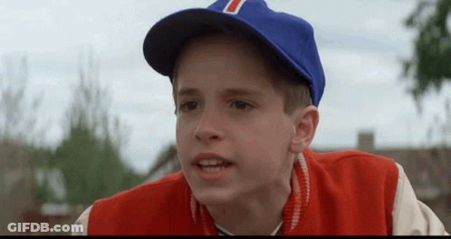 A Young Boy Wearing A Blue Baseball Cap With The Letter T On It GIF