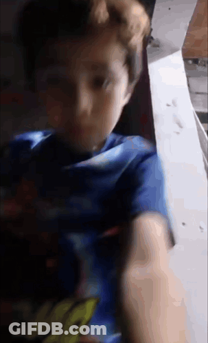 A Young Boy Wearing A Blue Shirt With The Word Spiderman On It Is Looking At The Camera . GIF