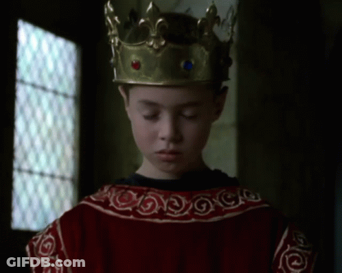 A Young Boy Wearing A Gold Crown And A Red Dress GIF