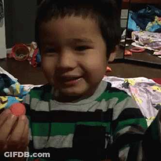 A Young Boy Wearing A Green And Black Striped Shirt Is Holding A Red Ball GIF