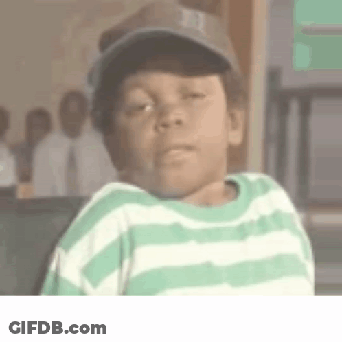 A Young Boy Wearing A Green And White Striped Shirt And A Baseball Cap Is Making A Funny Face . GIF