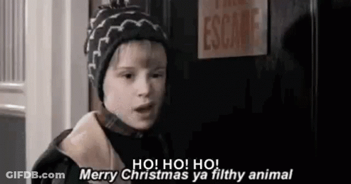 A Young Boy Wearing A Hat Is Standing In Front Of A Door And Saying Merry Christmas Ya Filthy Animal . GIF