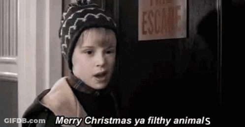 A Young Boy Wearing A Hat Is Standing In Front Of A Door . GIF