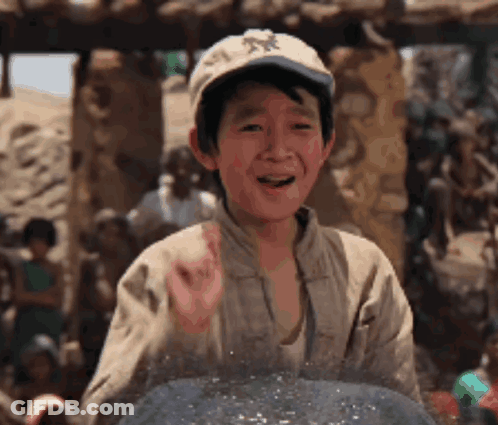 A Young Boy Wearing A Hat Is Standing In Front Of A Group Of People And Smiling . GIF