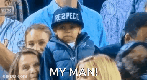 A Young Boy Wearing A Hat That Says Respect Is Sitting In A Crowd . GIF