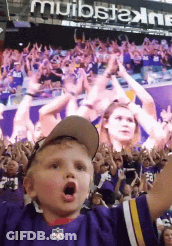 A Young Boy Wearing A Nfl Jersey Stands In A Crowd GIF