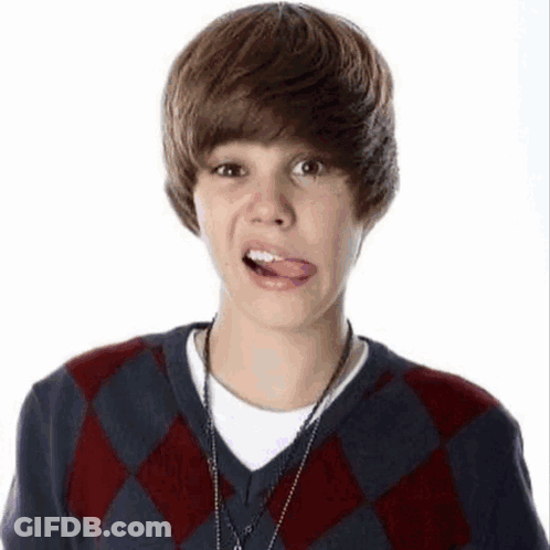A Young Boy Wearing A Plaid Sweater Is Sticking Out His Tongue . GIF