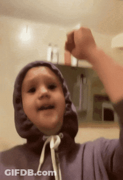 A Young Boy Wearing A Purple Hoodie Is Raising His Fist GIF