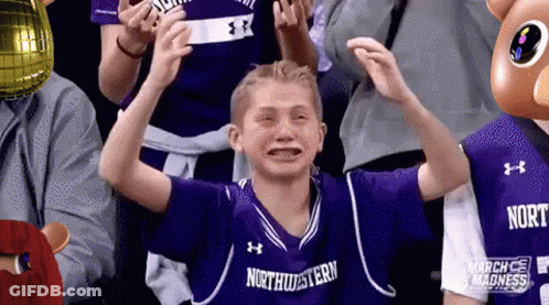 A Young Boy Wearing A Purple Northwestern Jersey Is Crying While Sitting In A Crowd . GIF