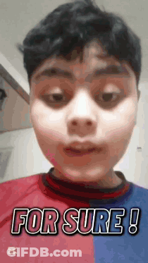 A Young Boy Wearing A Red And Blue Shirt Is Making A Funny Face . GIF