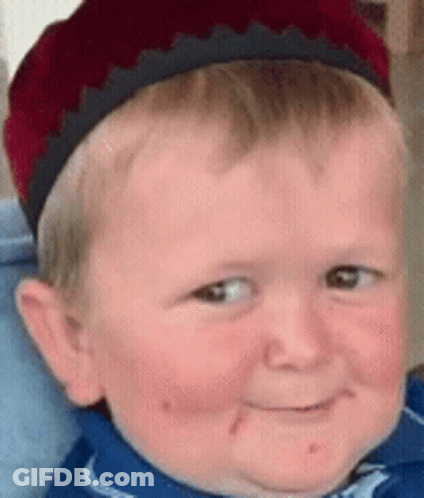 A Young Boy Wearing A Red Hat And A Blue Shirt Is Smiling GIF