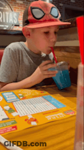 A Young Boy Wearing A Spider Man Hat Drinks A Drink Through A Straw GIF