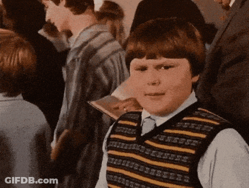 A Young Boy Wearing A Striped Vest Stands In A Crowd Of People GIF