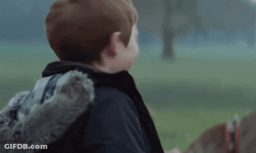 A Young Boy Wearing A Sweater And A Jacket Is Laughing GIF
