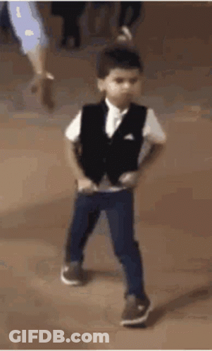 A Young Boy Wearing A Vest And Pants Is Dancing On A Dance Floor . GIF
