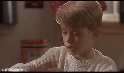 A Young Boy Wearing A White Sweater Is Looking At A Book GIF