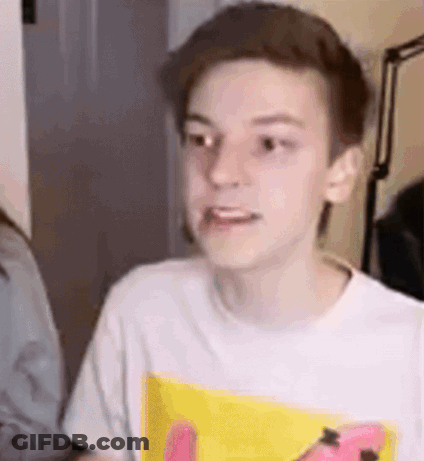 A Young Boy Wearing A White T-Shirt With A Yellow Spongebob Print Is Making A Face . GIF