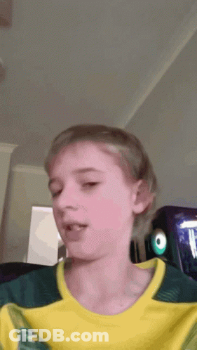 A Young Boy Wearing A Yellow And Green Shirt With The Letter T On It GIF