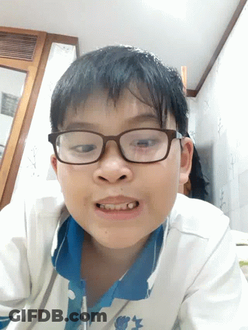 A Young Boy Wearing Glasses And A Blue Shirt Is Smiling For The Camera GIF